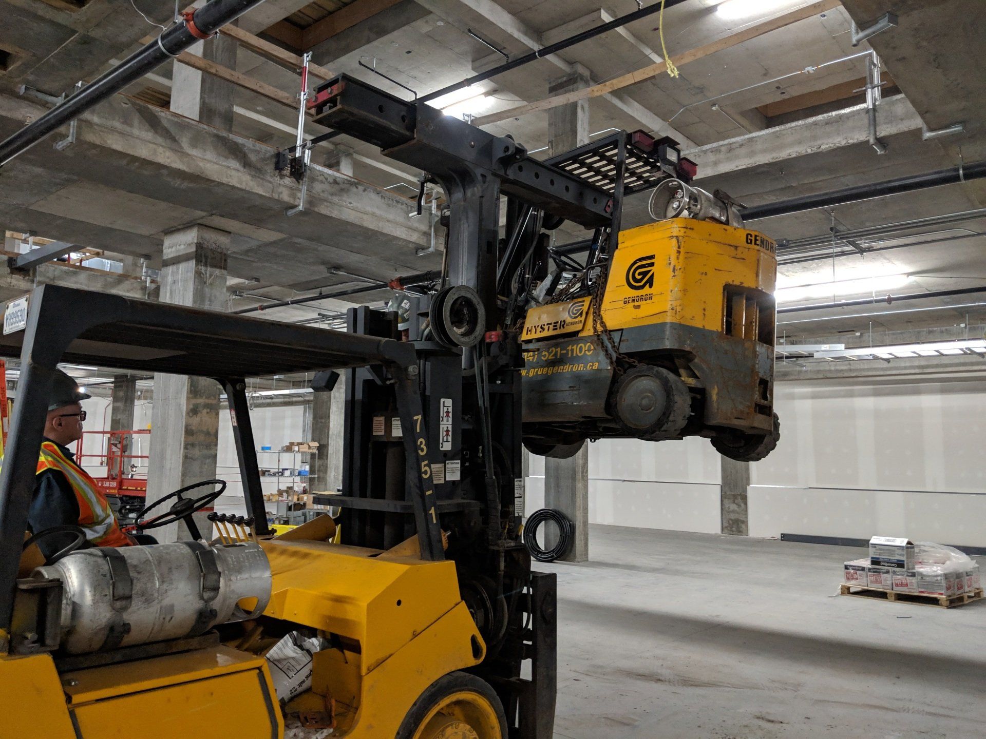 Un homme conduit un chariot élévateur jaune dans un entrepôt.