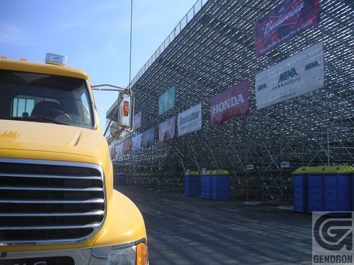 Un camion jaune est garé devant un bâtiment avec des panneaux indiquant Honda et Budweiser