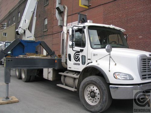 Un camion blanc est garé devant un bâtiment en brique