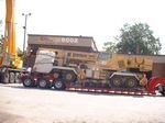 Un gros camion transporte une grue sur une remorque.