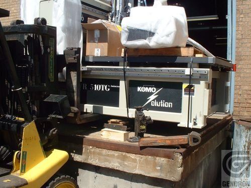 A forklift is carrying a machine that says komo solution