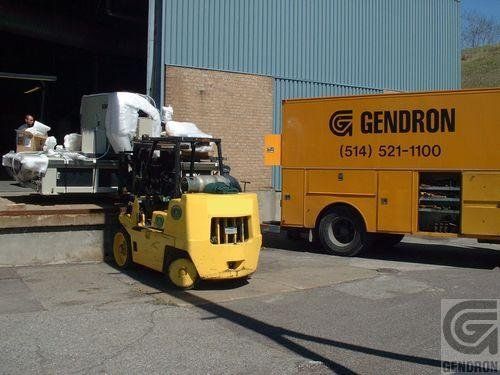 A yellow gendron truck is parked next to a forklift