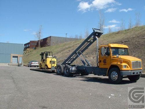 A yellow garbage truck with a forklift attached to it