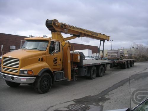 Un camion jaune avec une grue à l'arrière