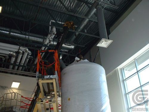 A large white tank is being built in a factory