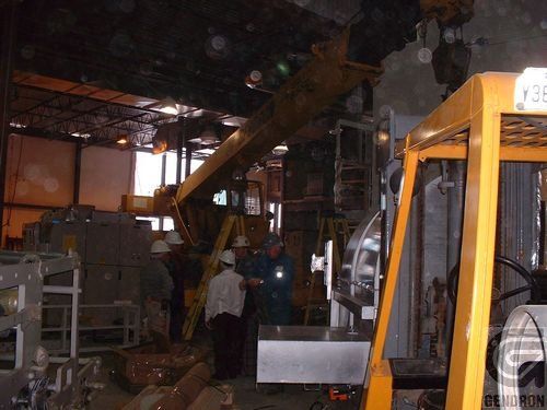 A yellow forklift is in a warehouse with workers