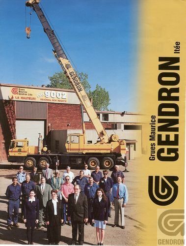 Un groupe de personnes debout devant un camion avec une grue dessus