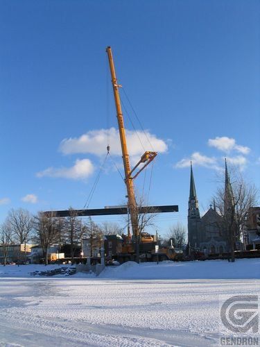 Une grande grue soulève un gros morceau de métal dans la neige