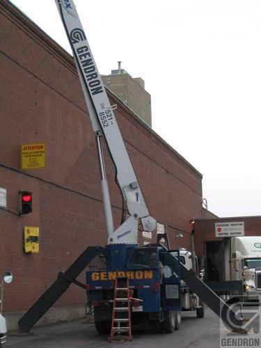 Une grue Gendron est stationnée devant un immeuble