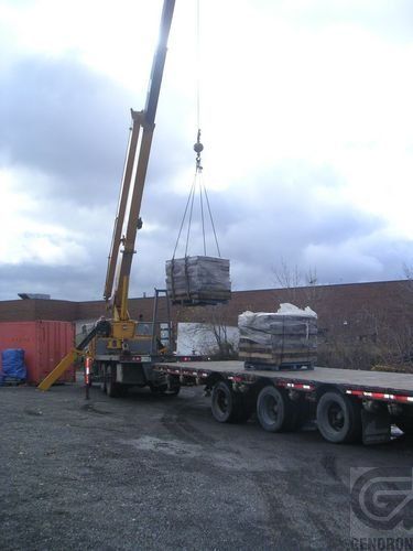 Une grue soulève une pile de briques d'une remorque