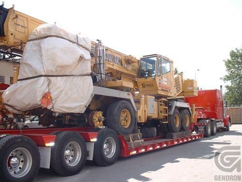 Une grande grue jaune est assise au sommet d'un semi-remorque