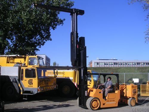 A man is driving a yellow forklift in a parking lot