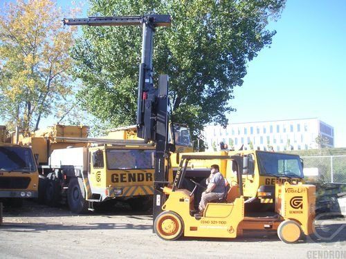 A forklift is parked next to a genor truck