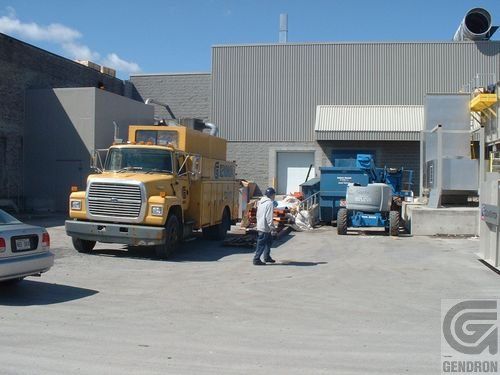 A yellow truck is parked in front of a building that says genoron