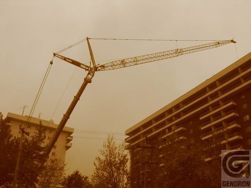 Une grande grue est en construction devant un bâtiment avec les lettres g dessus
