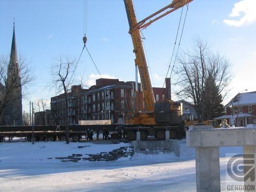 Une grande grue jaune soulève quelque chose dans la neige