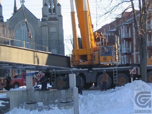 Une grande grue jaune est utilisée pour soulever un pont