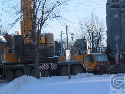 Un gros camion jaune avec les lettres g sur le côté est garé dans la neige