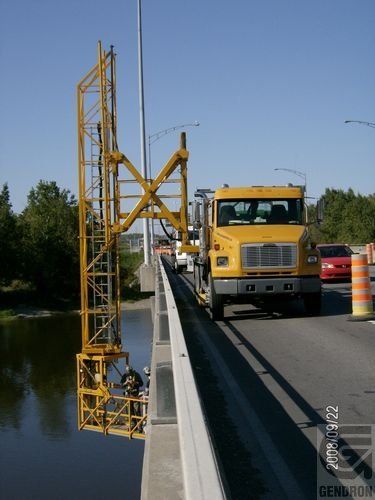 Un camion jaune est garé sur le côté d’un pont
