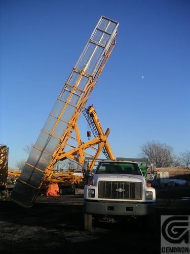 Un camion avec une échelle attachée est garé à côté d'un logo Genron