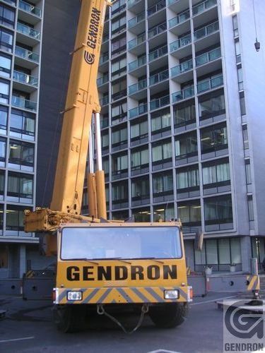 Un camion Gendron est stationné devant un immeuble en hauteur