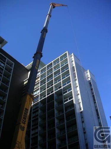 Une grande grue jaune se tient devant un grand bâtiment