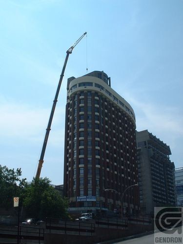 Un grand bâtiment en brique avec une grue devant qui dit Gendron