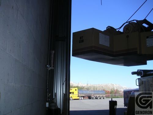 Une grande boîte en carton est soulevée par une grue avec les lettres g dessus