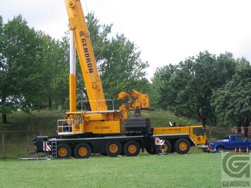 Une grue Gendron est stationnée dans un champ herbeux