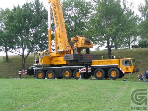Une grande grue jaune est garée dans un champ herbeux