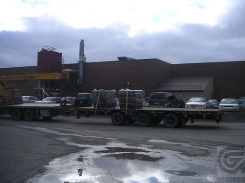 Un camion à plateau est garé devant un bâtiment en brique