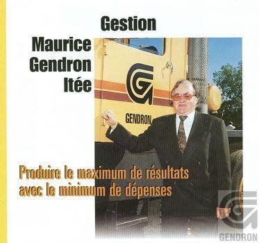 Un homme en costume-cravate se tient devant un camion sur lequel est écrit g