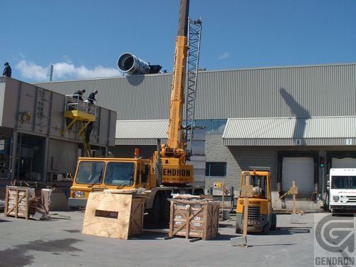 A large yellow crane is sitting in front of a building