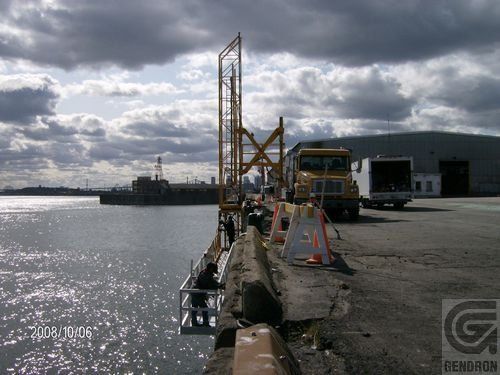 Un camion jaune est garé sur le bord de la route près de l’eau