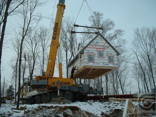 Une grue jaune soulève une maison dans les airs