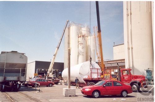 Une voiture rouge est garée devant une grue dans un parking