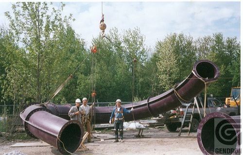Un gros tuyau est soulevé par une grue avec les lettres g en bas