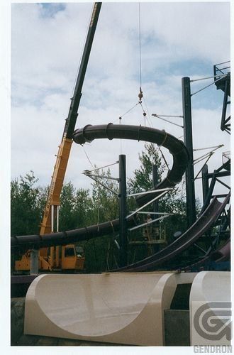 Une grande grue jaune lève un toboggan dans un parc aquatique