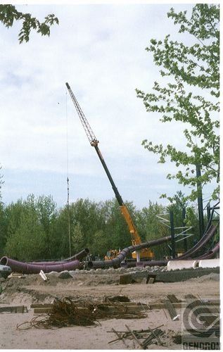 Une grande grue jaune est utilisée pour soulever un gros tuyau