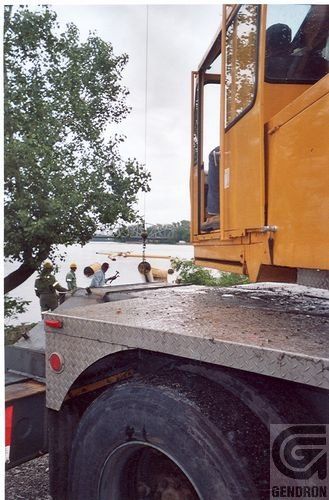 Un camion jaune est garé devant un plan d’eau