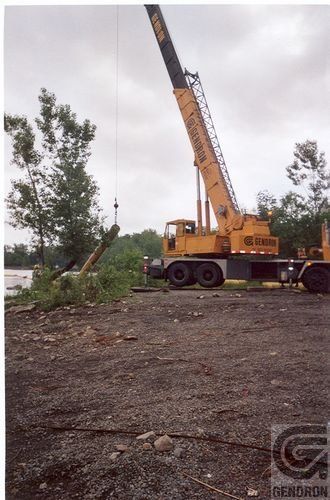 Une grande grue jaune est garée dans un terrain sale