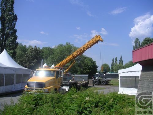 Un camion auquel est attachée une grue est garé devant un bâtiment qui dit Genoron