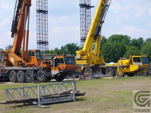 Plusieurs camions sont garés dans un champ herbeux avec un panneau indiquant denoron