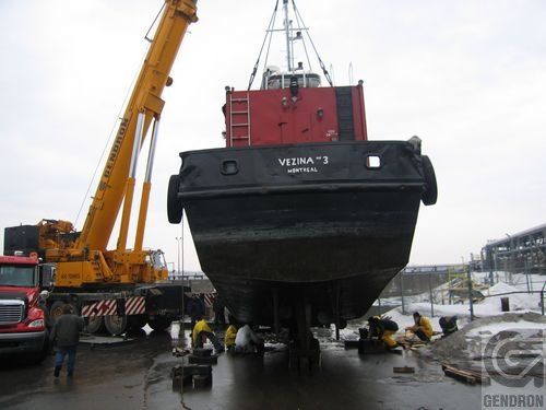 Une grue soulève un bateau portant le nom de Verna