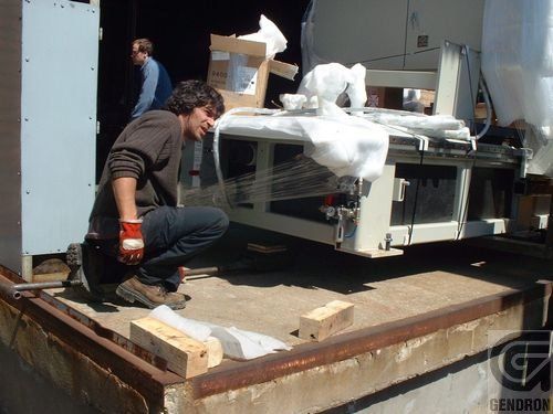 A man kneeling down next to a machine that says g on it