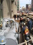 A group of construction workers are working on a large pipe.