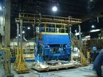 Une grande machine bleue est posée sur une palette en bois dans une usine.