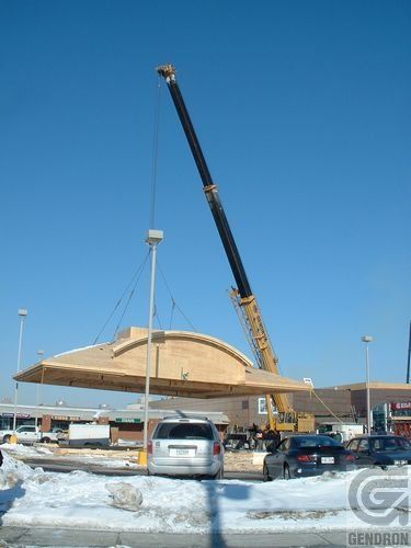 Une grande grue soulève un gros morceau de bois
