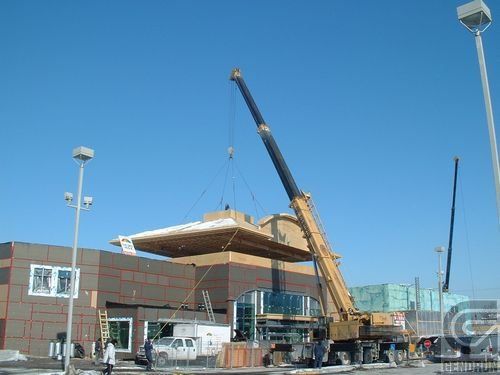 Une grue soulève un gros morceau de bois au-dessus d'un bâtiment