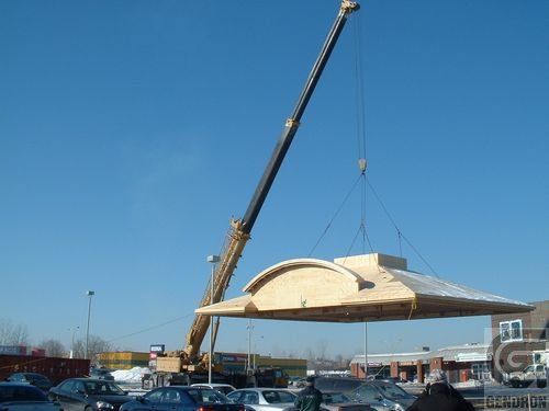 Une grue soulève un gros morceau de bois dans un parking